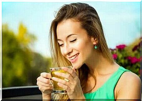 A woman smiling and drinking tea