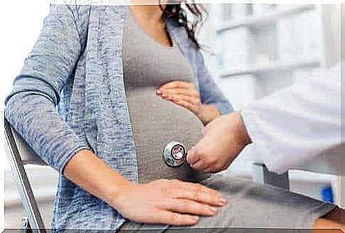 Doctor with a stethoscope on a pregnant belly