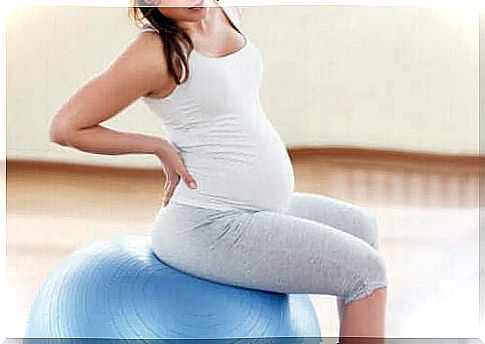 A pregnant woman is sitting on a pilates ball