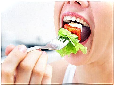 Woman putting a big bite of lettuce in her mouth